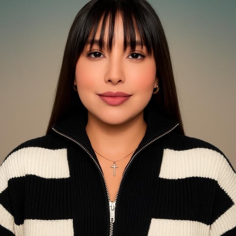 Woman with long dark bangs wearing a black and white striped zip-up cardigan with a cross necklace against a neutral background